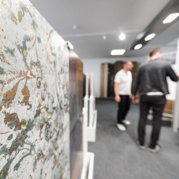 Moderne XXL Fliese in der Schärfe, dahinter findet eine Beratung in der Fliesenausstellung statt.