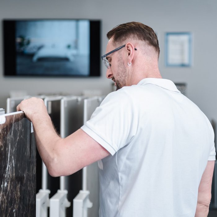 Geschäftsführer Thomas Jähler begutachtet die Fliesen in der Fliesenausstellung